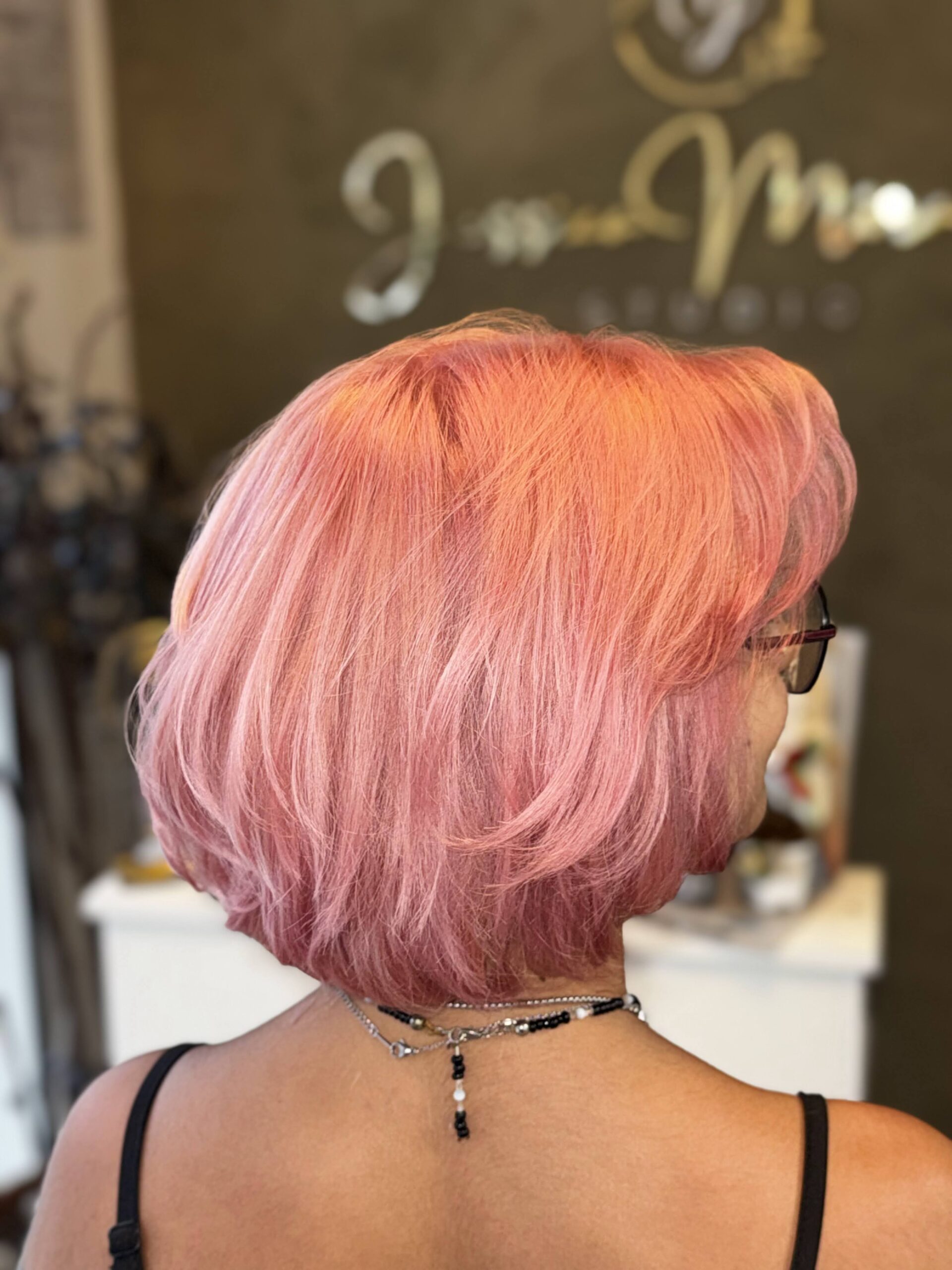 Mulher de costas com corte bob curto rosa vibrante, feita no Studio Jessica Miranda, salão de beleza em Cabo Frio